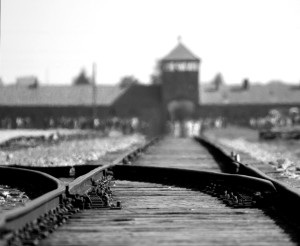 Blick über eine Eisenbahnweiche auf markante Gebaeude der heutigen Gedenkstaette Auschwitz