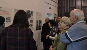 Unser Foto zeigt Erwachsene beim Blick auf die Ausstellung "Different Wars"am internationalen Holocaust-Gedenktag 2018 in der Geschichtswerkstatt.