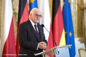 Dieses Foto zeigt den deutschen Bundespräsidenten Frank-Walter Steinmeier bei einer Ansprache vor mehreren Fahnen.