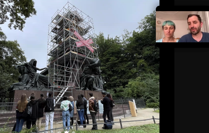 Blick auf das gut sechs Meter hohe, eingerüstete Bismarck-Denkmal im Großen Tiergarten in Berlin. Zuschauer beobachten die Arbeiten. Das Künstler-Duo Various & Gould ist oben rechts im Bild zu sehen. 