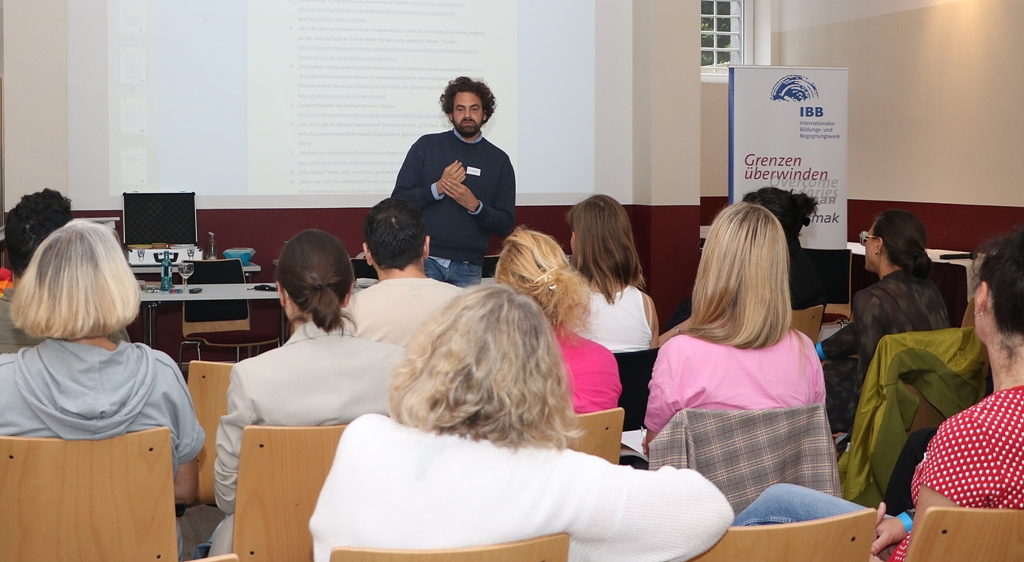 Referent Shai Hoffmann steht in einer offenen und einfühlsamen Haltung vor den Workshopteilnehmerinnen und - teilnehmern und bespricht Handlungsstrategien gegen Rassismus und Antisemitismus. 