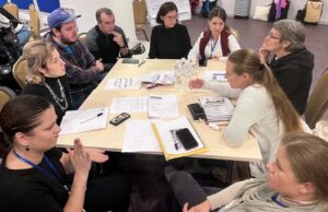 Unser Foto zeigt diskutierende Menschen mit und ohne Behinderungen an einem Tisch.