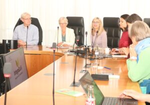Barbara Brunsing, Bürgermeisterin der Stadt Dortmund, sitzt hinter einem Mikrofon an einem Seminartisch neben Christoph Struß, Hanna Perfetti und Aliaksandra Kurylovich und richtet ein Grußwort an die Teilnehmerinnen und Teilnehmer des Projekts Integration durch Nachhaltigkeit, kurz IntegraDuN. 