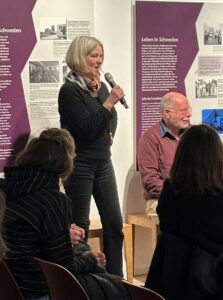 Renate Müller vom Verein IN-Gesellschaft hält das Mikrofon in der Hand und spricht.